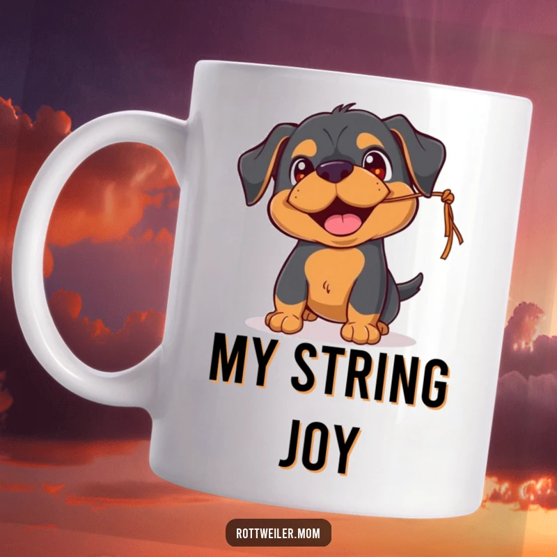 Funny Rottweiler mug featuring a playful pup with happy eyes, joyfully batting at a dangling string, full of mischievous fun.