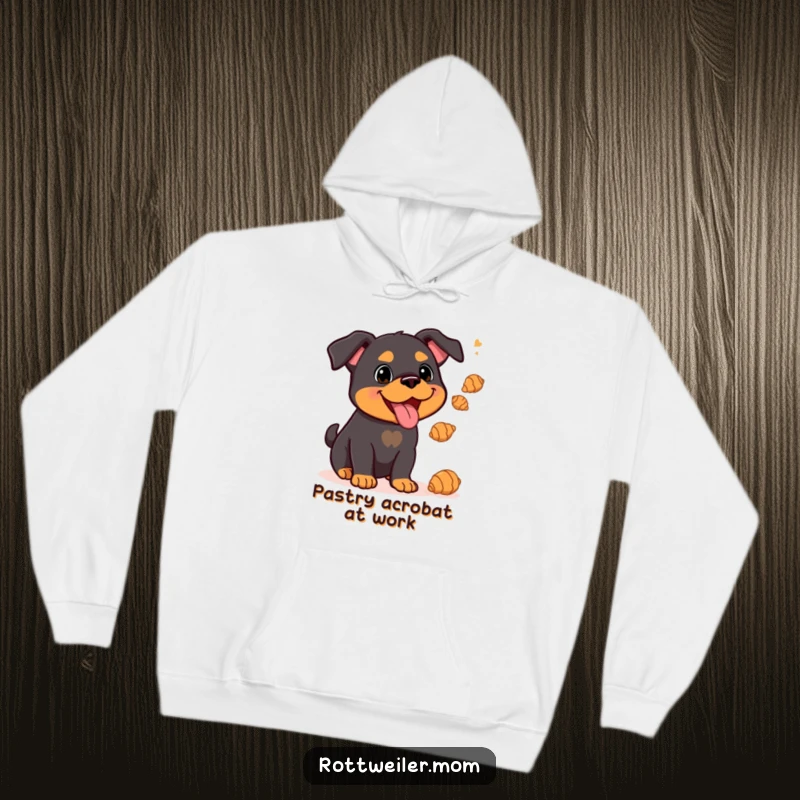 Funny Kawaii Rottweiler juggling delicate croissants on a cozy hoodie, a heartwarming and humorous design.