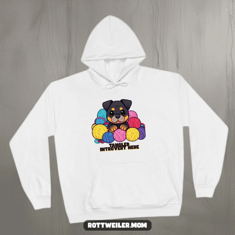 Funny Kawaii Rottweiler peeking from a colorful pile of yarn balls on a cozy hoodie, a heartwarming design.