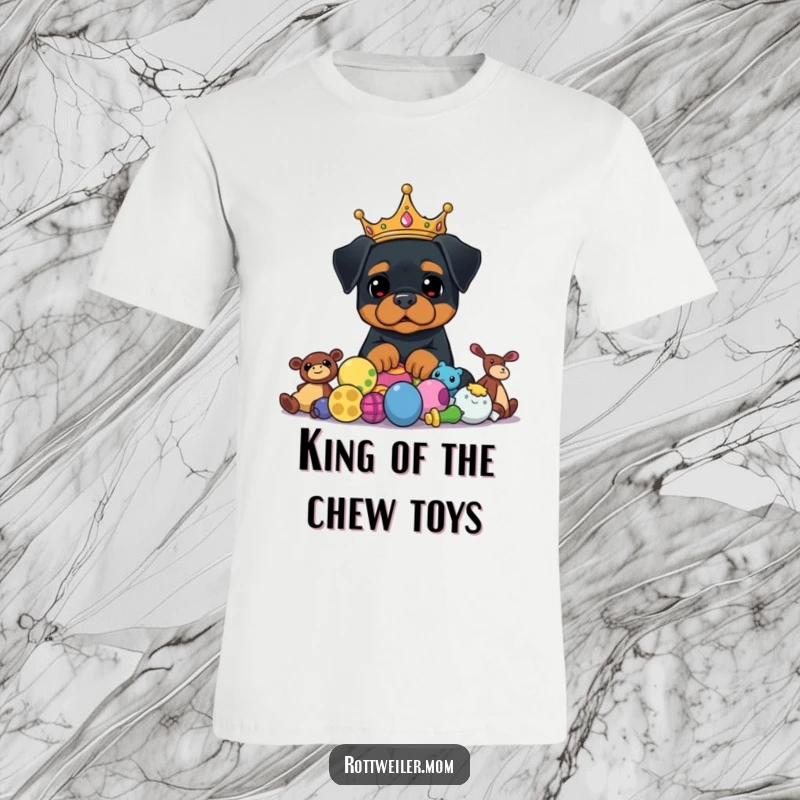 Funny Rottweiler King T-Shirt features a regal dog in a crown, proudly watching over a pile of scattered toys, radiating fun.